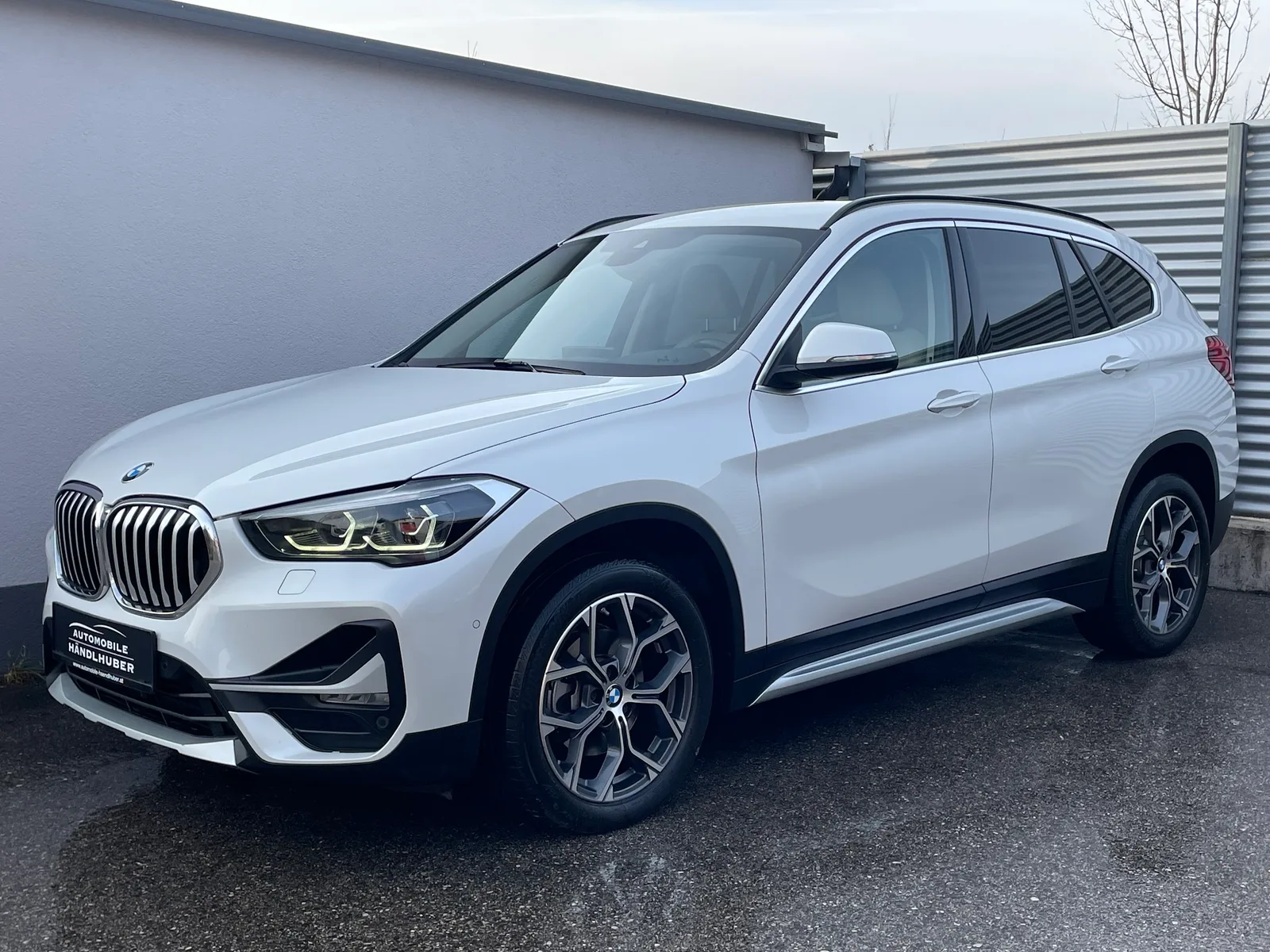 Weißer BMW X1 vor einer hellen Hallenwand