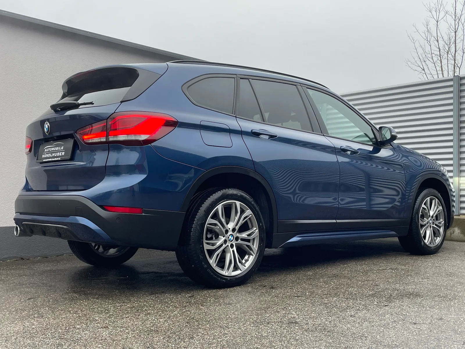 Blauer BMW X1 von hinten mit Händlerkennzeichen